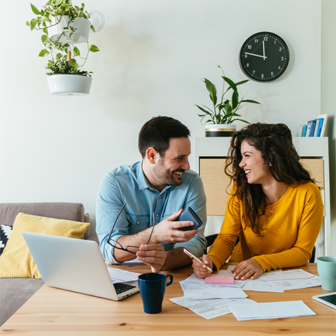 couple laughing and smiling while paying bills_480x480