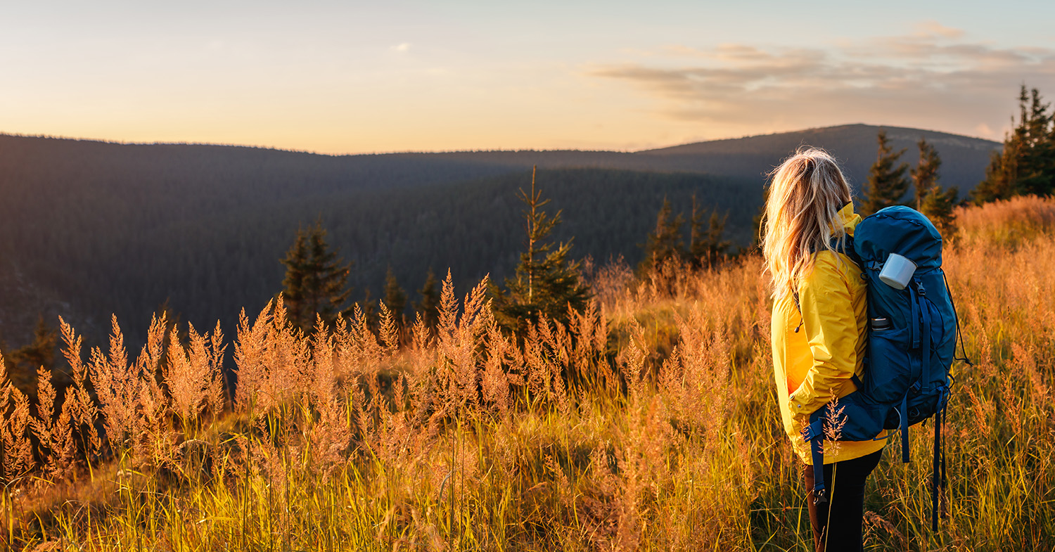 woman watching the sunset while hiking_1500x785