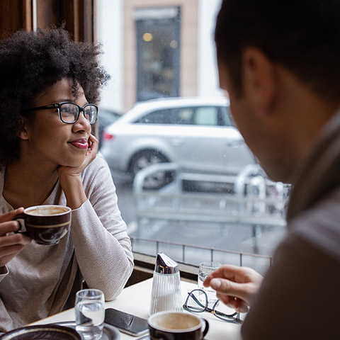 man and woman sitting in a cafe and enjoying coffee together