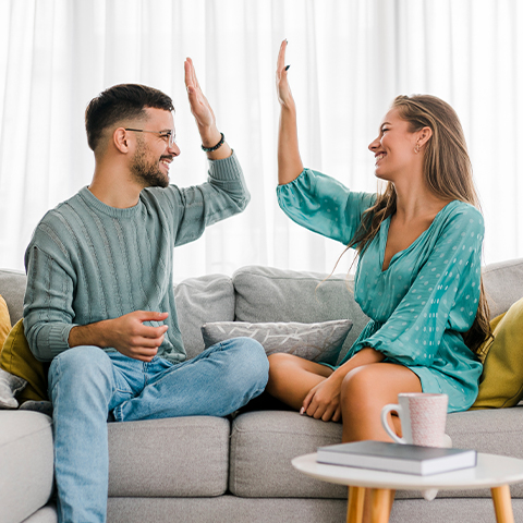 man and a woman high fiving on a couch_480x480