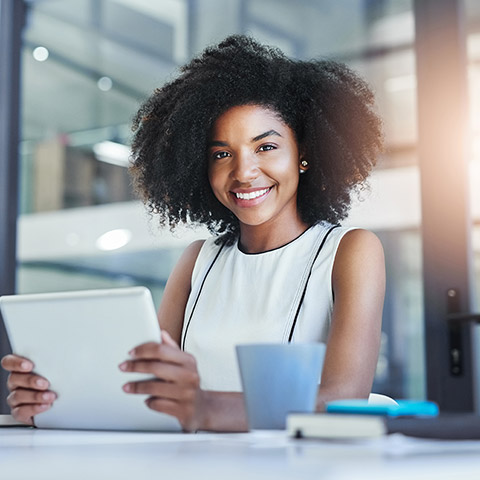 Woman sitting at a conference table holding papers while looking at her laptop