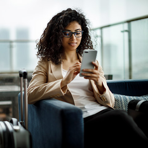 Woman sitting in an airport chair looking at her mobile phone